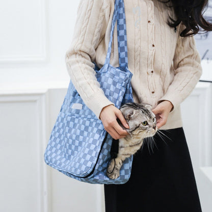 Cat carrier bag in blue check carried on the shoulder with a cat peeking out