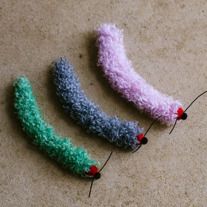 Green, blue-gray and light purple caterpillar toys side by side