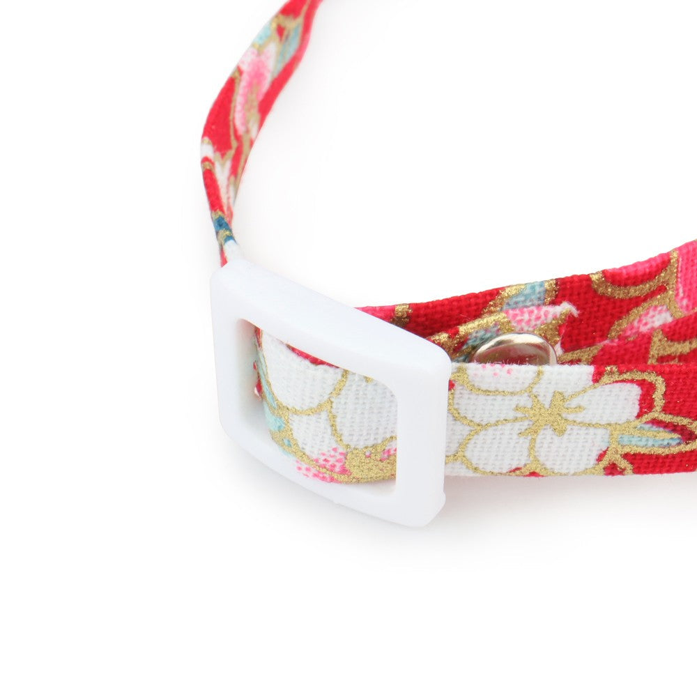 Close-up of the white plastic buckle on the red cherry blossom collar