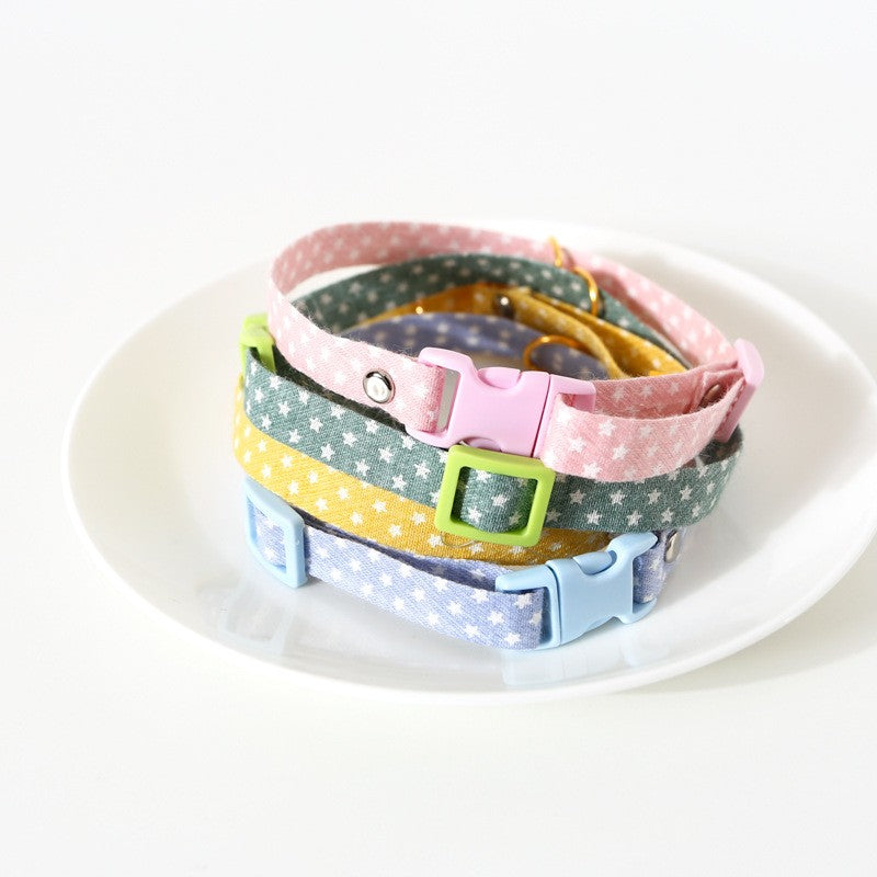 Stack of colourful cloth cat collars with charms in a dish