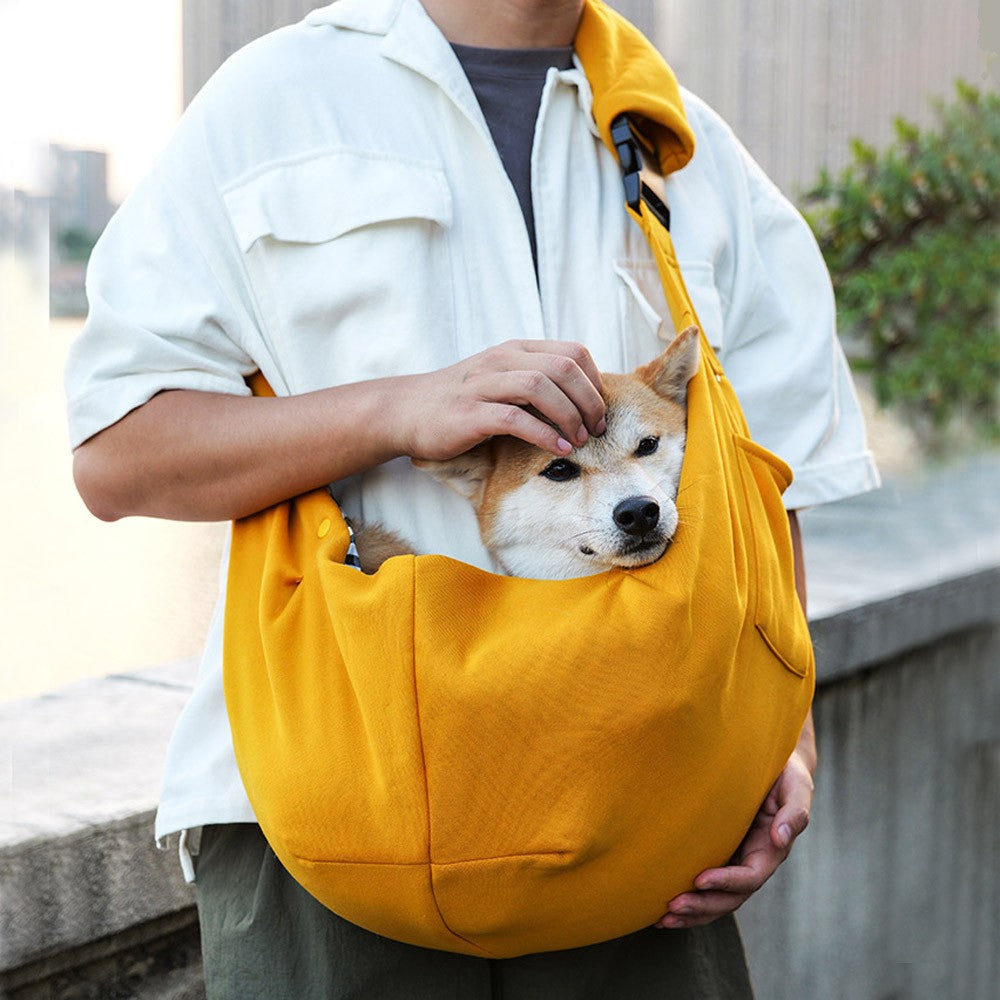 Dog sling carrier in yellow worn across the chest with a Shiba Inu inside