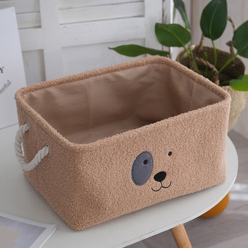 Brown plush dog toy box with a cartoon puppy face and rope handles