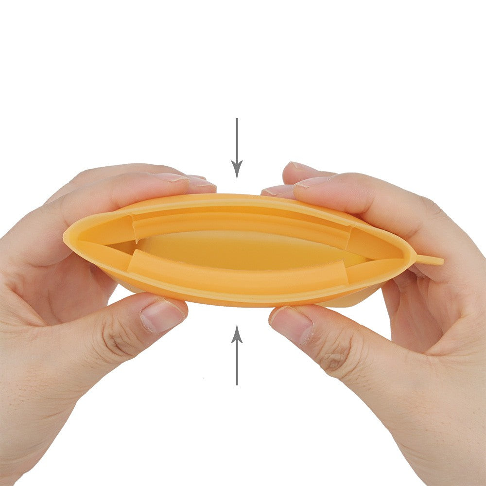Squeezing the sides of the silicone treat pouch to pop the mouth open