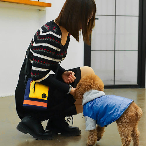 Woman wearing the dog walking bag while greeting a poodle