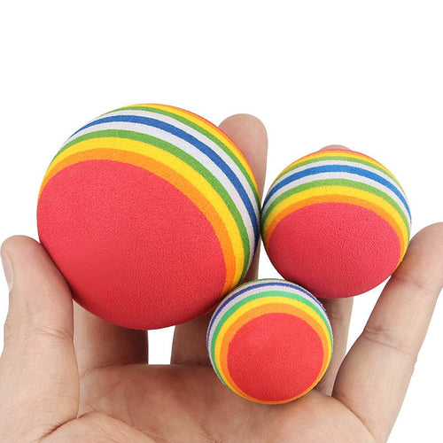 Three rainbow foam balls for cats held in a hand