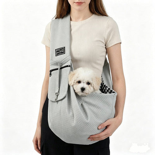 Front dog carrier sling in light gray worn with a small white dog