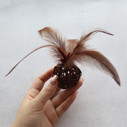 Brown rattan ball with long feathers held in a hand