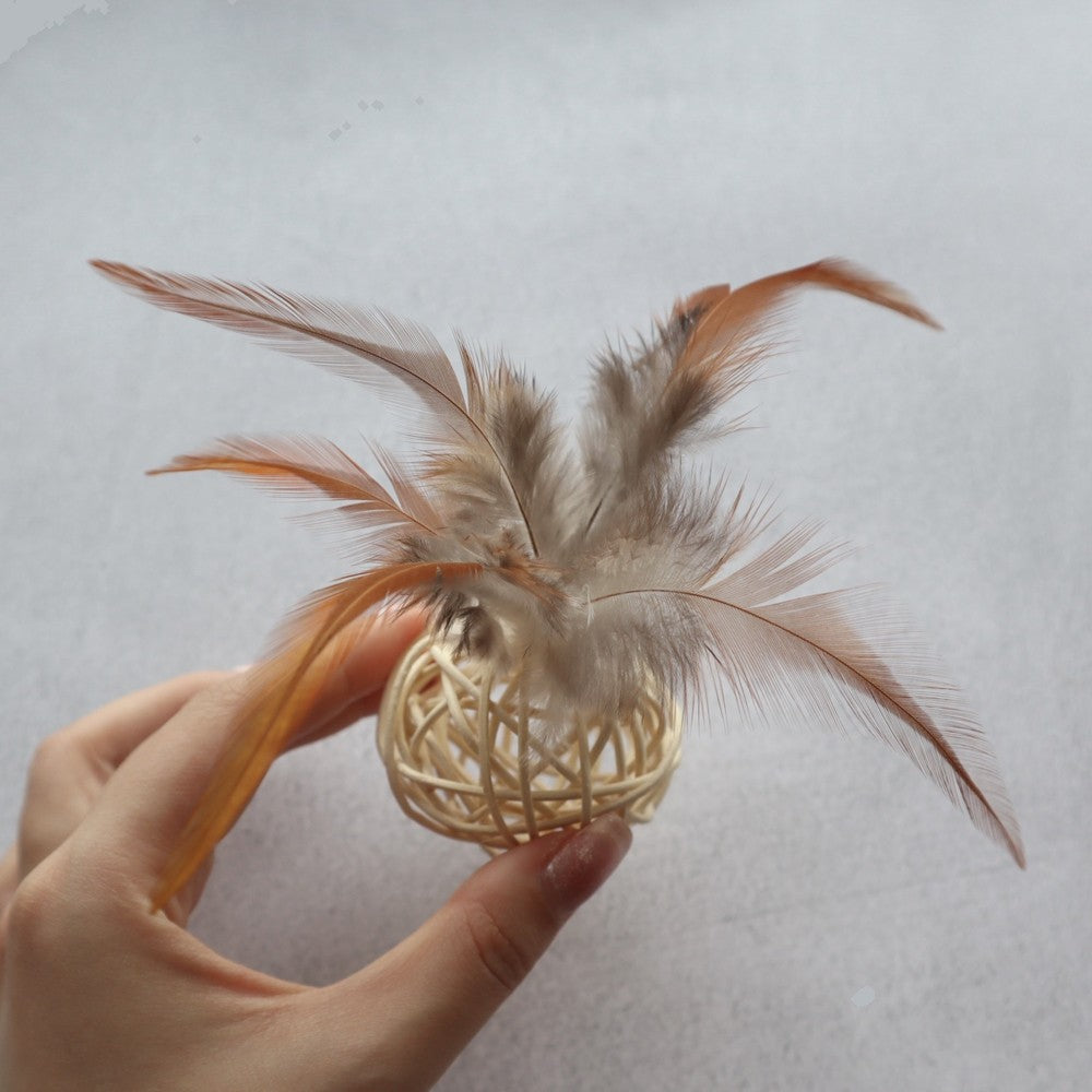 Beige rattan ball with feathers held in a hand