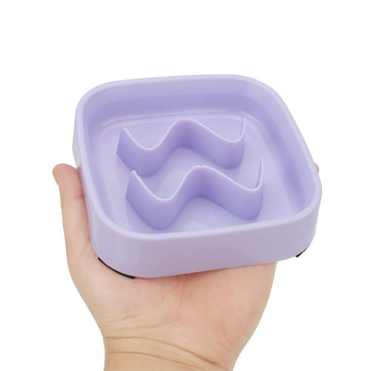 Hand holding the purple square slow eating dog bowl to show its size