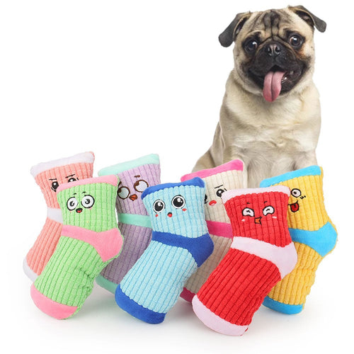 Pug sitting behind a pile of colourful squeaky sock dog toys with smiley faces
