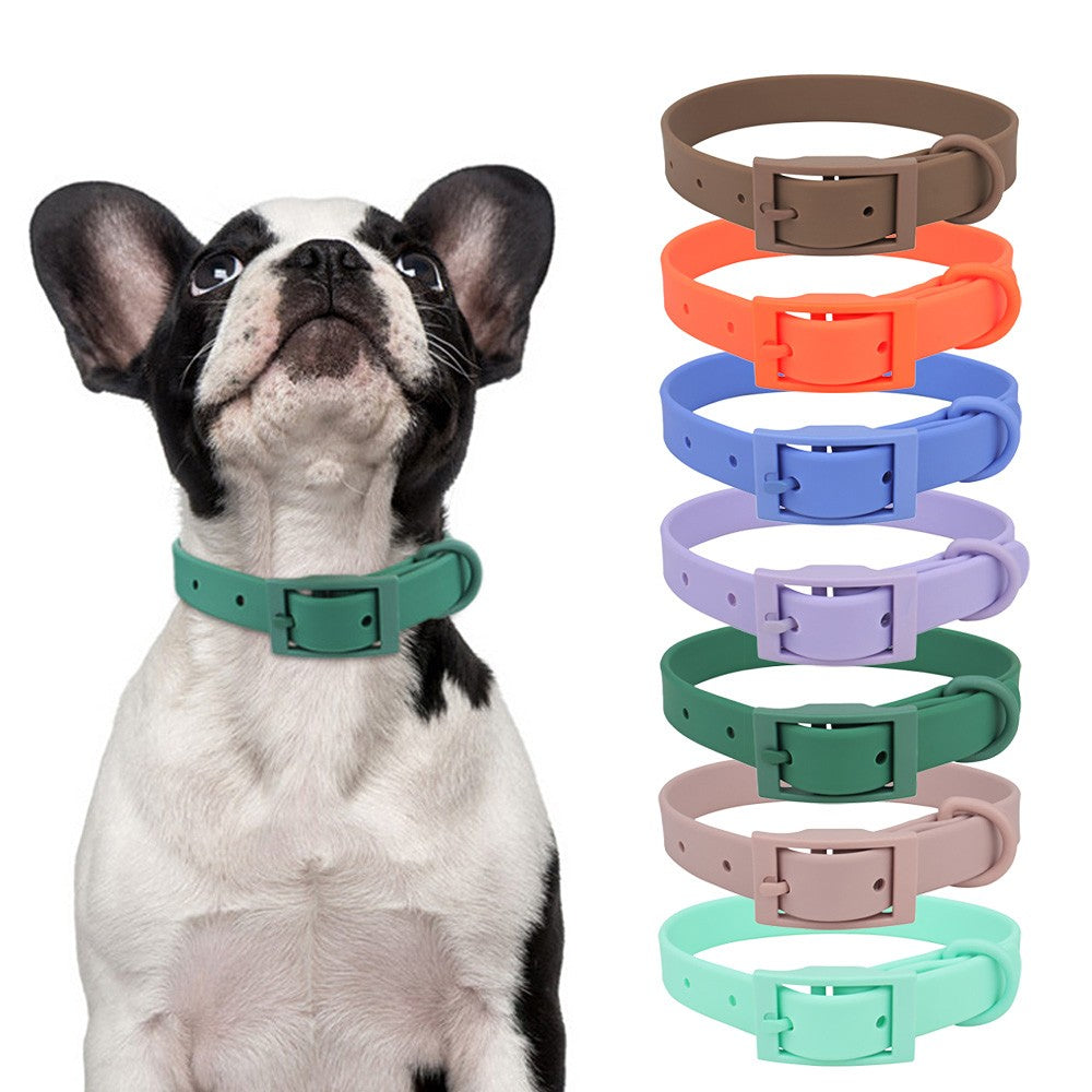 French bulldog in a green waterproof collar beside a stack of colour-matched PVC collars
